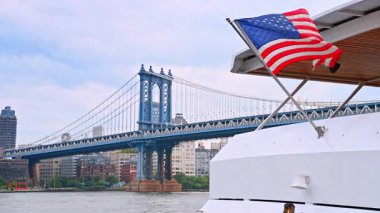 Teknede Amerikan bayrağı sallıyor. Muhteşem Manhattan Köprüsü ve New York silueti.