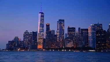 Günümüz New York 'unun göz kamaştırıcı silueti, alacakaranlıkta ABD. Nehirden şehre alçak açılı görüş.