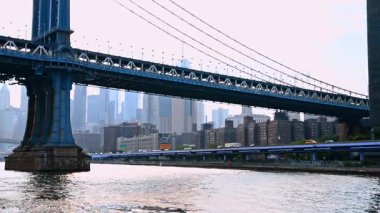 New York, ABD, 8 Temmuz 2025: Doğu Nehri kıyısı boyunca otoyol boyunca birden fazla araba hareket ediyor. Nehir manzarasından Manhattan Köprüsü 'nün alçak açılı görüntüsü.