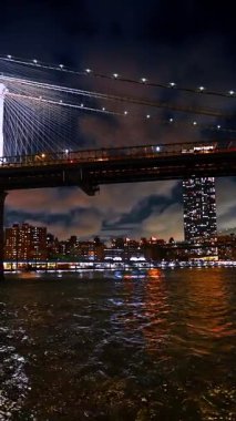 Brooklyn Köprüsü yakınlarındaki East River 'ın su manzarasından New York' un ufuk çizgisi. Metropolün üstündeki bulutlu gökyüzünün alçak açılı görüntüsü. Dikey video.