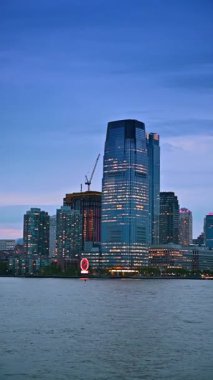 Nehir manzarasından alacakaranlık şehri silueti. New York, ABD 'de nehir turu. Dikey video.