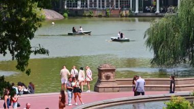New York, ABD, 8 Temmuz 2025: Güneşli Central Park, New York, ABD. İnsanlar gölün rıhtımında fotoğraf çekiyor. Bazı insanlar arka planda kayıkla geziyor..