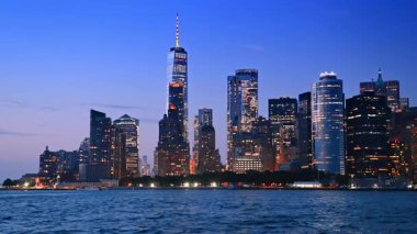 Alacakaranlıkta New York 'un güzel parlak silueti. Nehir manzarasının göz kamaştırıcı yüksek binaları ve gökdelenleri alçak açılı..