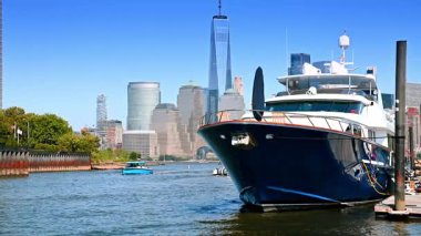 Jersey, NJ, ABD 'deki rıhtıma demirli büyük koyu mavi tekne. Küçük tekneler kameraya yaklaşıyor. Arkaplanda Manhattan silueti.