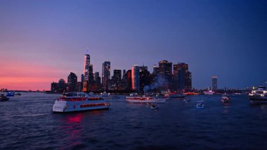 New York, ABD, 8 Temmuz 2025: Çok sayıda tekne alacakaranlıkta Doğu Nehri 'nin karanlık sularında toplandı. Muhteşem pembe gökyüzü ve Manhattan gökyüzü arkaplanda gökyüzü.