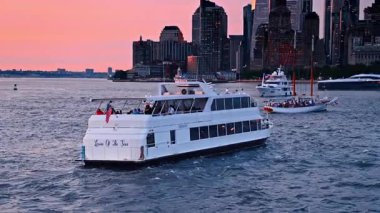 New York, ABD, 8 Temmuz 2025: Günbatımında Doğu Nehri 'nin su manzarasında çeşitli tekneler duruyor. Pembe gökyüzünün arkaplanındaki New York silueti.