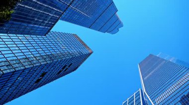 Modern bir şehrin gökdelenlerine bakıyorum. New York, ABD 'nin cam gökdelenleri açık mavi gökyüzünün zemininde.