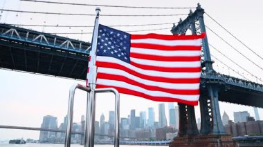 Teknenin metal korkuluklarında Amerikan bayrağı. Manhattan Köprüsü 'ne yaklaşıyoruz. Düşük açı. Arka planda New York 'un puslu silüeti.