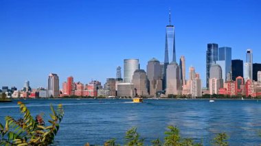 Jersey City 'den gelen parlak güneş ışığında, Manhattan' ın göz kamaştırıcı ufuk çizgisinde Hudson Nehri 'ni izleyin. Tekneler bir yaz günü su kenarında seyahat ederler..