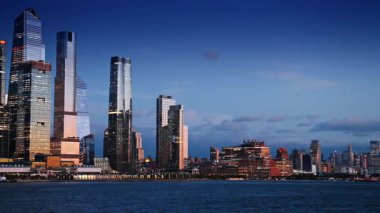 Manhattan 'ın gelecekteki gökdelenleri batan güneşin ışığını yansıtıyor. Nehir manzarasından New York şehir merkezinin gökyüzüne bakın..