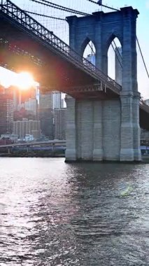 Brooklyn Köprüsü, New York üzerinde günbatımı var. Brooklyn Köprüsü, gün batımında, New York şehrinin silueti ve East River üzerinde güneş ışığıyla..