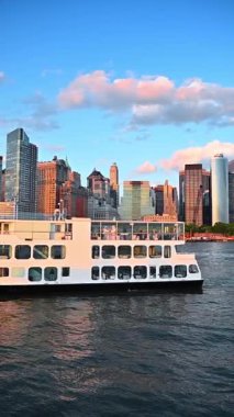 Gün batımında Manhattan ufuk çizgisinde feribot kalkıyor. Yolcu feribotu gün batımında Manhattan siluetiyle birlikte Doğu Nehri boyunca yol alıyor..