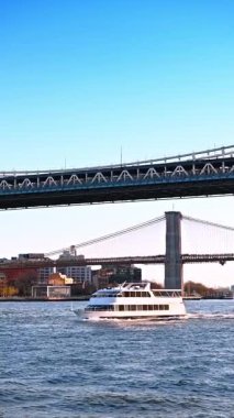 Brooklyn ve Manhattan Köprülerinin altından geçen tekne. Manhattan ve Brooklyn Köprüleri 'nin altından Doğu Nehri boyunca beyaz bir tekne geçiyor.