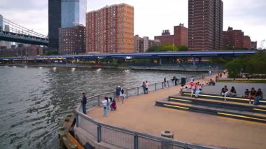 New York, ABD, 1 Ağustos 2025: Manhattan 'daki East River rıhtım güvertesi. Aşağı Manhattan, New York 'taki East River gezinti alanında yürüyen ve dinlenen insanların görüntüsü.