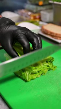 Şef taze marul doğruyor. Restoranın mutfağında yeşil bir tahtada kesilmiş marulun yakın plan görüntüsü..