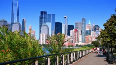 Jersey City, ABD, 11 Temmuz 2025, Jersey City 'nin ufuk çizgisi ile rıhtım gezisi. Gezinti alanı boyunca yürüyen insanlar Jersey City ve Manhattan siluetlerini net bir şekilde görüyorlar..