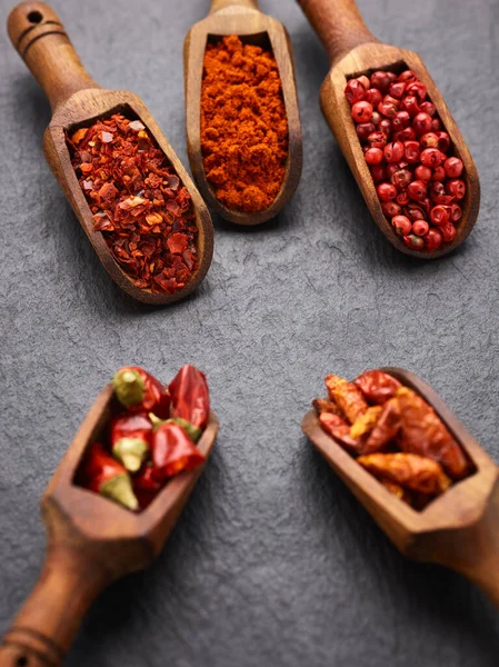 红辣椒 红辣椒 胡椒和茴香在黑石表面的木制勺子里 — 图库照片