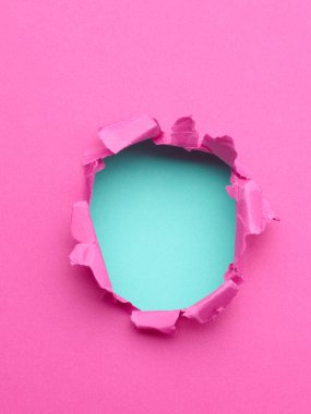 Ortasında delik olan yırtık pembe bir kağıt.