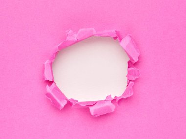 Ortasında delik olan yırtık pembe bir kağıt.