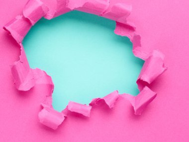 Ortasında delik olan yırtık pembe bir kağıt.