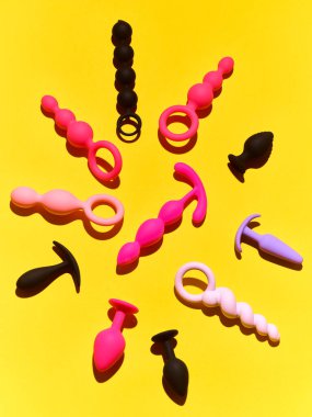 Bright sex toys background. anal plugs and dildo over yellow paper backdrop