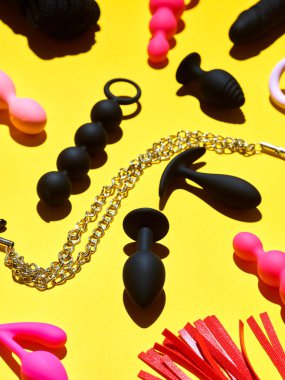 Bright sex toys background. anal plugs and dildo over yellow paper backdrop