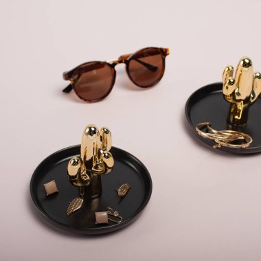 Beyaz arka planda lüks mücevherleri olan bir tutucu, mesaj için yer var. Altın elementlerle en düşük moda kompozisyonu. Altın kaktüs