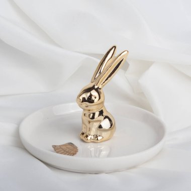 Beyaz arka planda lüks mücevherleri olan bir tutucu, mesaj için yer var. Altın elementlerle en düşük moda kompozisyonu. Altın Tavşan