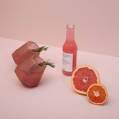 Zarif ve modaya uygun pembe altın kokteyl bardakları turunçgil meyveleri ve pembe arka planda biberiye.