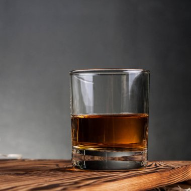 Ahşap masa ve siyah arka planda viski bardağı. Model şablonu.