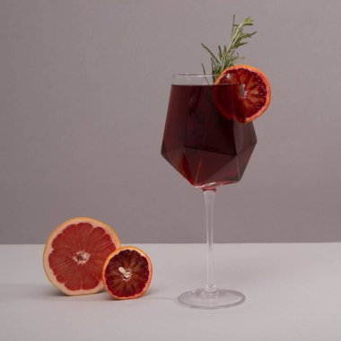 Gri masa ve gri arka planda şarap kadehi. Zarif bir moda ve narenciye ve biberiyeli kokteyl kadehi. Model şablonu.