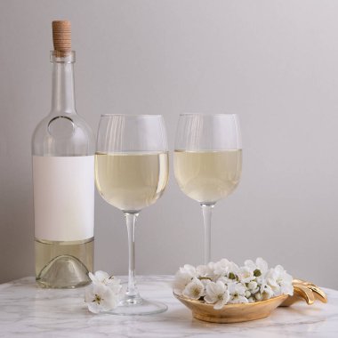 Şık moda, şık saplı cam, gri arka planda beyaz şarap ve şişe. Yaz sanatı içeceği konsepti. Model şablonu