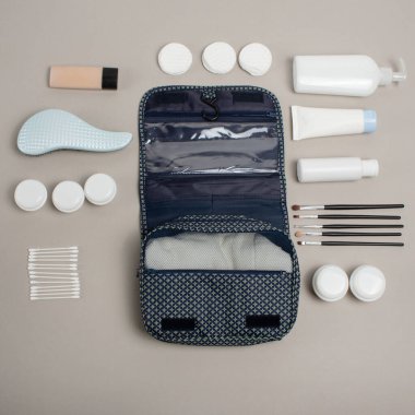 Seyahat kozmetik seti gri arka planda. Tuvalet eşyası çantası. Gri renkli beyaz kadın kozmetik şişeleri. Bir grup plastik koruma şişesi. Tasarım için boş alan. Beyaz Kozmetik kapları kümesi, kopya alanı ile üst görünüm.