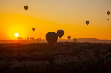 Kapadokya, Türkiye: 22 Kasım 2022: Kapadokya 'da gün doğumu, Türk sıcak hava balonları sarı gökyüzünün arka planında uçuyor.