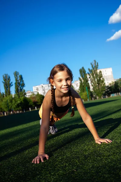 stock image Teenage girl athlete at the stadium is training and doing physical exercises in the summer outside