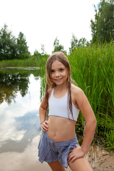 運動ティーンエイジャー少女は自然 夏の季節 曇った空の湖の近くを歩きます ロイヤリティフリーのストック画像