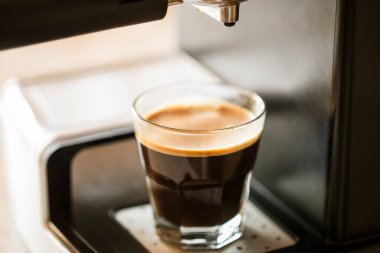 Cup of espresso shot closeup with coffee machine