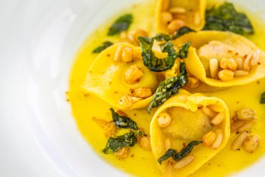 Pesto soslu İtalyan ıspanaklı ravioli, parmesan ve sedir fıstığı. Lüks gurme yemekler, beyaz tabakta İtalyan mutfağı. Makro yemek fotoğrafı, lezzetli yemekler, yemek geçmişi.