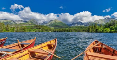 High Tatras dağlarında sakin panoramik sabah manzarası. Ulusal park ormanı, Strbske Gölü, Slovakya. İnanılmaz doğa manzarası, güneşli mavi gökyüzü, ahşap tekneler. Sükunet özgürlük macera geçmişi