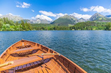Kozalaklı ormanlı dağ gölü, ahşap tekne güneşli mavi gökyüzü, cennet gibi özgürlük yolculuğu geçmişi. Romantik turist mekanı. Ulusal Park Lisesi Tatras, Avrupa. Güzel doğa manzarası cennet gibi.