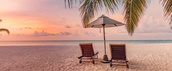 美丽的热带岛屿夕阳西下 情侣们在棕榈树叶下坐着伞 白色的沙滩 地平线 田园诗般的夜空 刺激海滩度假胜地的全景 浪漫的天堂海滩横幅 — 图库照片