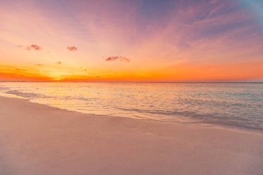 Sahilde. Güzel panoramik manzara, altın renkli günbatımı gökyüzü bulutları. Kumlu sahilde dalgaların hafifçe vurduğu sakin bir deniz. İnanılmaz gün doğumu manzarası, yaz doğası, huzurlu sahil.