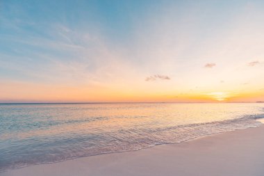 Sahilde. Güzel panoramik manzara, altın renkli günbatımı gökyüzü bulutları. Kumlu sahilde dalgaların hafifçe vurduğu sakin bir deniz. İnanılmaz gün doğumu manzarası, yaz doğası, huzurlu sahil.