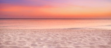 Sahilde. Güzel panoramik manzara, altın renkli günbatımı gökyüzü bulutları. Kumlu sahilde dalgaların hafifçe vurduğu sakin bir deniz. İnanılmaz gün doğumu manzarası, yaz doğası, huzurlu sahil.