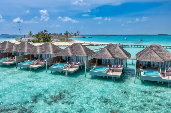 Güzel Maldivler cenneti. Tropik hava seyahati manzarası, deniz manzarası ahşap köprü iskelesi, su villaları, inanılmaz deniz kıyısı gökyüzü plajı, tropikal ada doğası. Egzotik bir yer, en iyi yaz tatili.