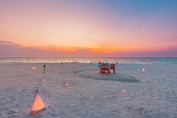 日没の空の下でろうそくと砂の上のビーチで素晴らしいロマンチックなディナー ロマンスと愛 豪華な目的地ダイニング 海の景色とエキゾチックなテーブルセットアップ ストック写真