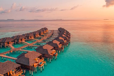 Gün batımında adada bungalovlu okyanus manzarası