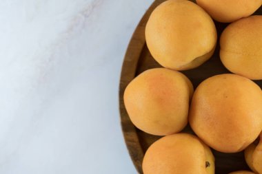 Tahta bir tabakta olgun kayısılar, üst manzara. Taze doğal kayısılar, lezzetli yaz tatlısı mermer tezgahta, yakın plan, yüksek çözünürlüklü..