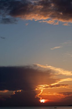 Gün batımında güneş ışığı alan dramatik bulutlar, deniz kıyısından yakalanır.