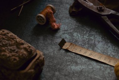 Terzinin eski alet ve aksesuarlarından oluşan bir hayat. Makas, mezura, deri kumaş, dikiş kutusu gibi. Malzemeleri karanlık ve kasvetli bir şekilde dikiyorum.